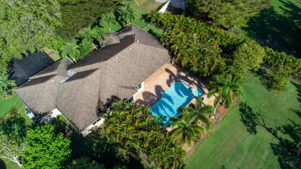 an aerial view of residential house with outdoor space and trees all around