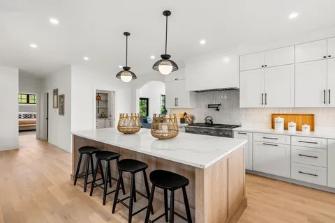 a kitchen with stainless steel appliances granite countertop a sink a stove and a wooden floors