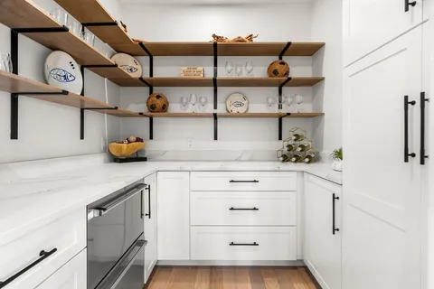 a kitchen with stainless steel appliances kitchen island granite countertop a stove a sink a refrigerator and white cabinets with wooden floor