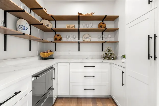 a kitchen with stainless steel appliances kitchen island granite countertop a stove a sink a refrigerator and white cabinets with wooden floor