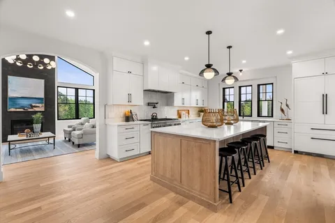 a kitchen with stainless steel appliances kitchen island granite countertop a stove a sink a refrigerator and white cabinets with wooden floor