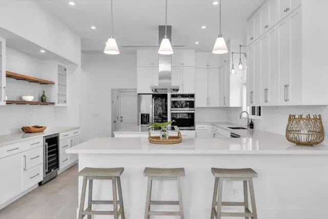 a kitchen with stainless steel appliances a large counter top a stove a chimney a sink and a refrigerator