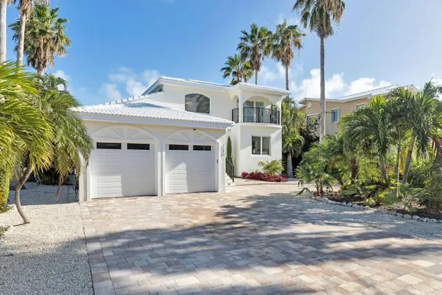 a view of a white house with a yard and palm trees