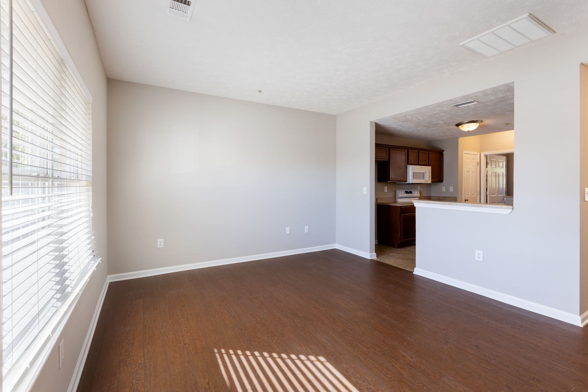 1007 Wells Way Spring Hill, TN 37174 - Photo 5 of 15 an empty room with wooden floor kitchen view and windows