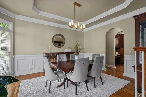 a kitchen with stainless steel appliances granite countertop a stove top oven a sink dishwasher a dining table and chairs with wooden floor