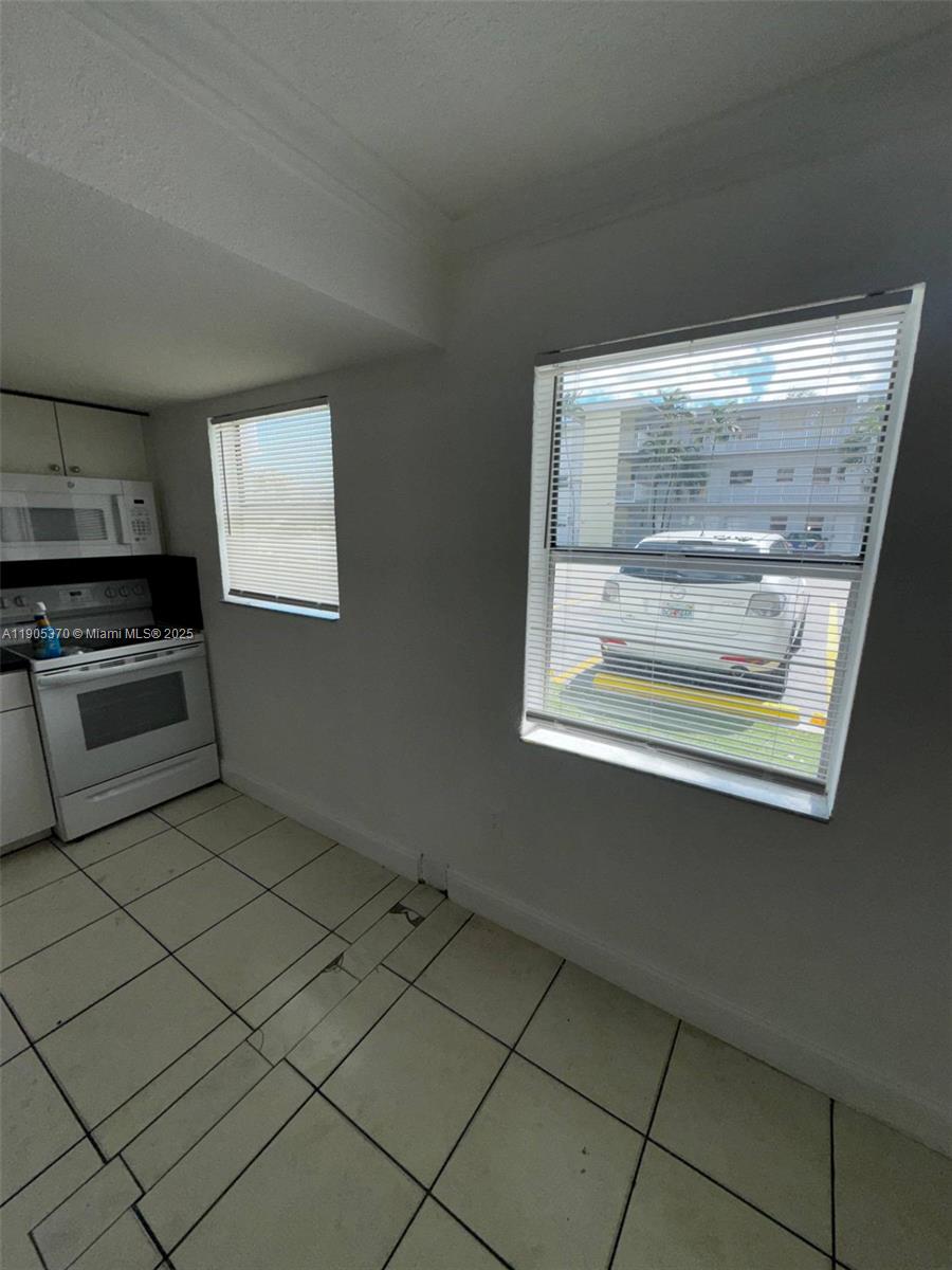 5150 West 12th Avenue, Unit 115 Hialeah, FL 33012 - Photo 3 of 14 a kitchen with a white cabinets and a stove top oven