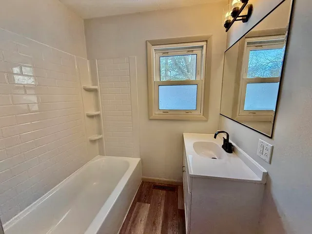 a bathroom with a tub a sink and a window