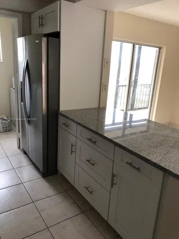 a kitchen with granite countertop a refrigerator and cabinets