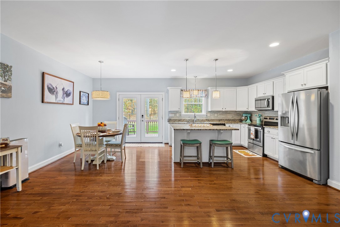 4875 Kimber Lane Gum Spring, VA 23065 - Photo 21 of 48 a kitchen with stainless steel appliances granite countertop a refrigerator a stove top oven a dining table and chairs with wooden floor