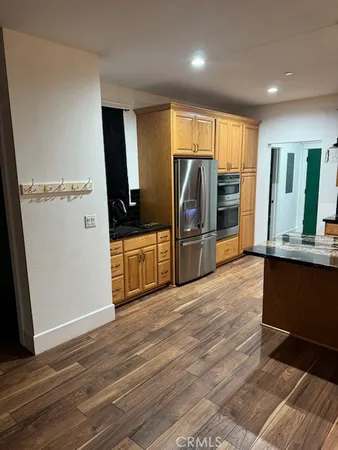 a view of a kitchen with wooden floor electronic appliances and windows