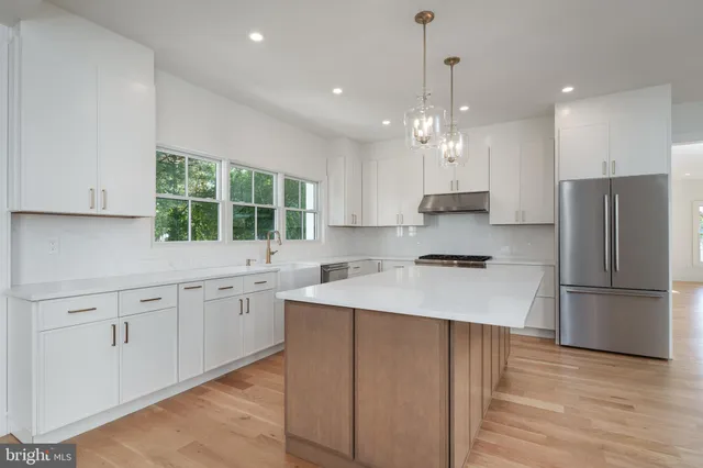 a kitchen with kitchen island white cabinets and stainless steel appliances