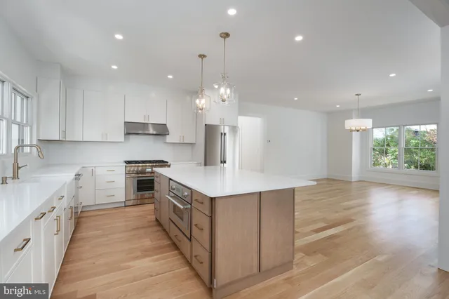 a kitchen with a stove a sink a center island and windows