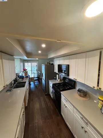 a kitchen that has a lot of cabinets a sink and wooden floor