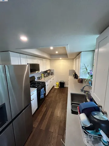 a kitchen with stainless steel appliances a refrigerator a stove a sink dishwasher with a dining table and chairs with wooden floor