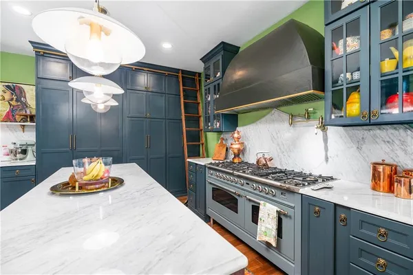a kitchen with stainless steel appliances a stove a chimney and a dining table