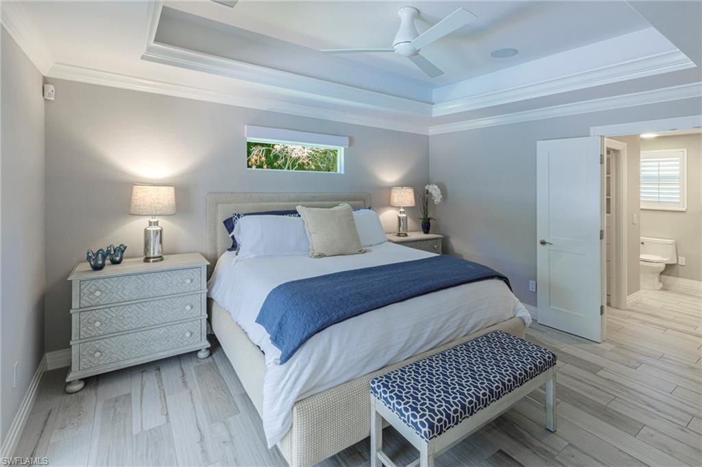 3720 Parkview Way Naples, FL 34103 - Photo 13 of 29 Bedroom featuring ceiling fan, a tray ceiling, and light wood-type flooring
