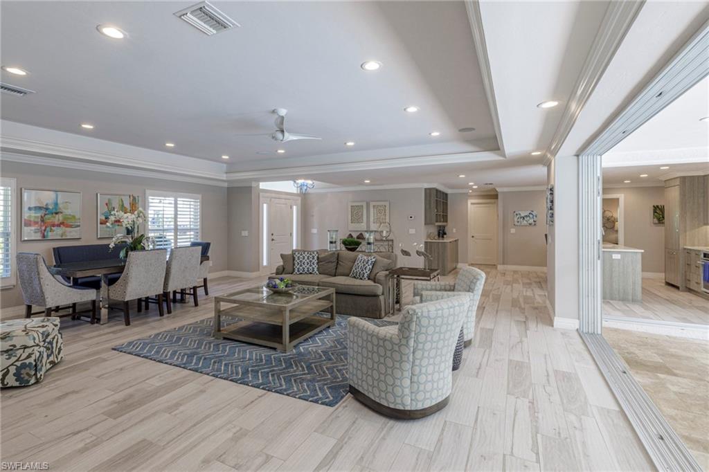 3720 Parkview Way Naples, FL 34103 - Photo 17 of 29 Living room with ceiling fan, a raised ceiling, crown molding, and light wood-type flooring