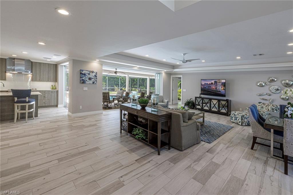 3720 Parkview Way Naples, FL 34103 - Photo 2 of 29 Living room featuring ceiling fan, a raised ceiling, light hardwood / wood-style flooring, and crown molding