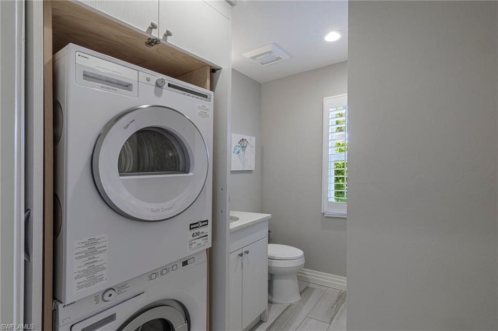 3720 Parkview Way Naples, FL 34103 - Photo 28 of 29 Laundry room featuring light hardwood / wood-style floors and stacked washer and dryer