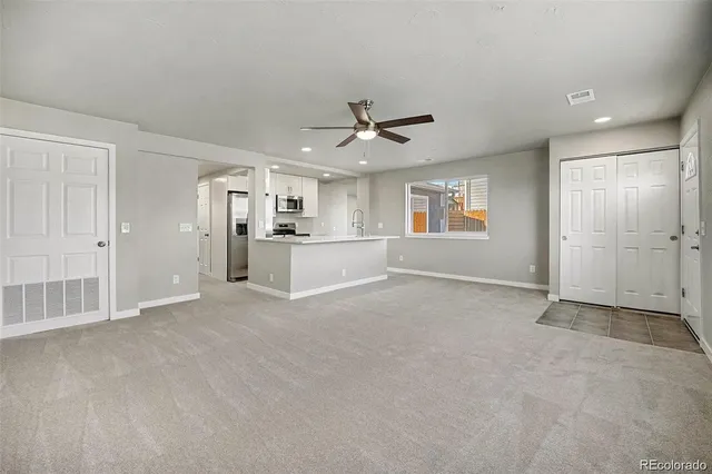 an empty room with windows and ceiling fan
