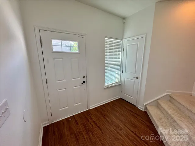 an empty room with wooden floor closet and windows