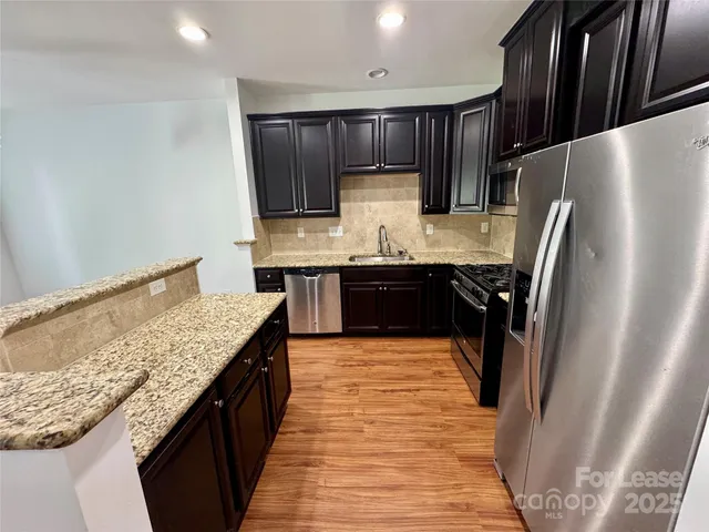 a kitchen with stainless steel appliances granite countertop refrigerator sink and cabinets