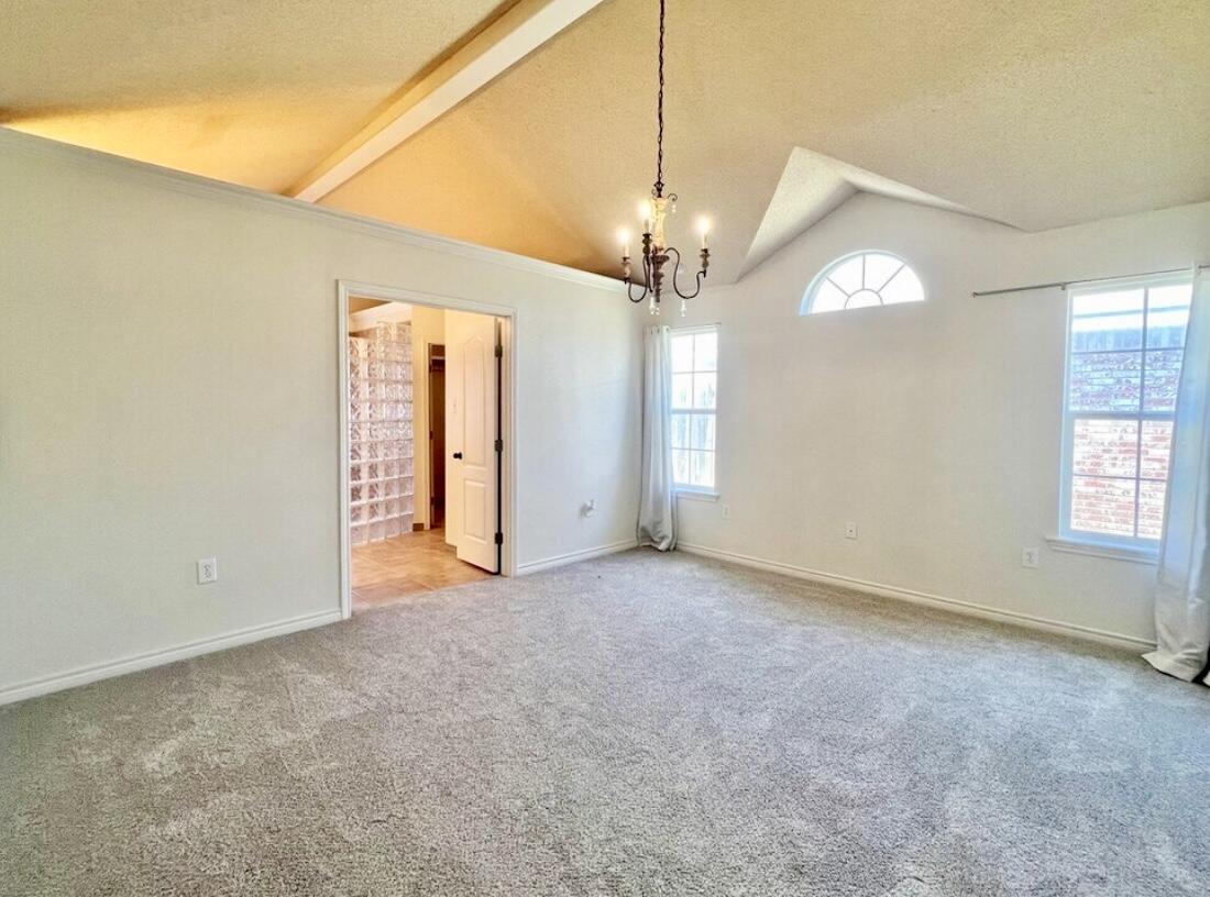 6805 36th Street Lubbock, TX 79407 - Photo 11 of 12 an empty room with chandelier fan and windows