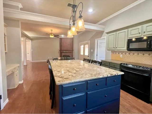 a bathroom with a granite countertop sink a large mirror and a wooden cabinets