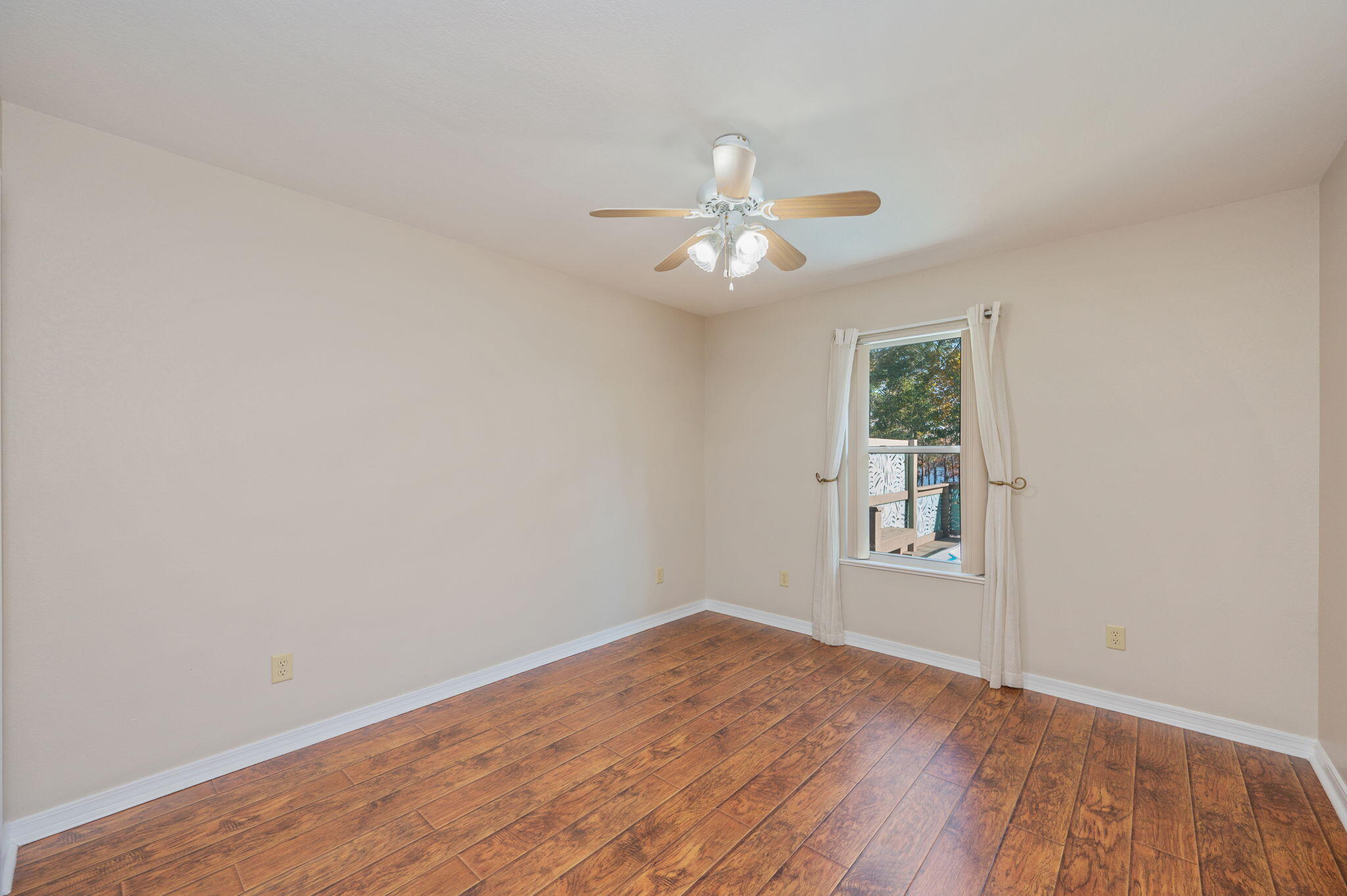 516 Blue Pond Circle Ponce de Leon, FL 32455 - Photo 26 of 39 an empty room with wooden floor chandelier fan and windows