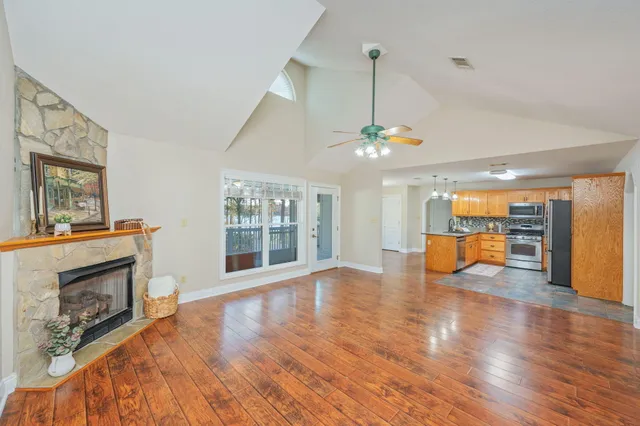 a view of an empty room with wooden floor fireplace and a window