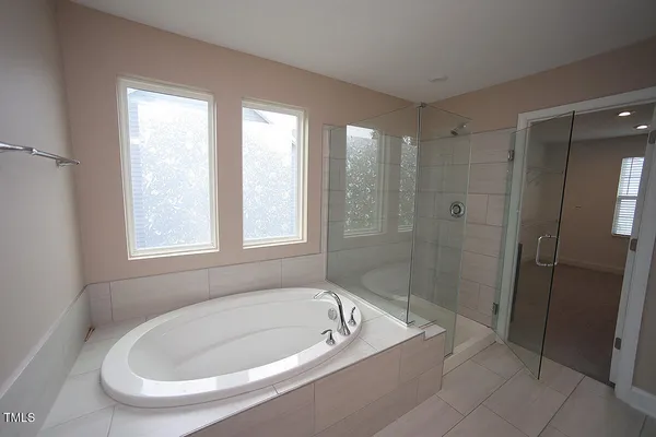 a bathroom with a tub a window and a shower