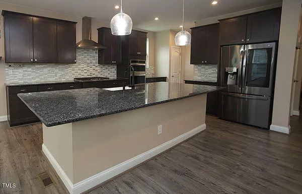a kitchen with stainless steel appliances granite countertop a sink a refrigerator and a granite counter tops