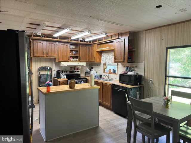 a kitchen with kitchen island a stove a sink a refrigerator and a dining table