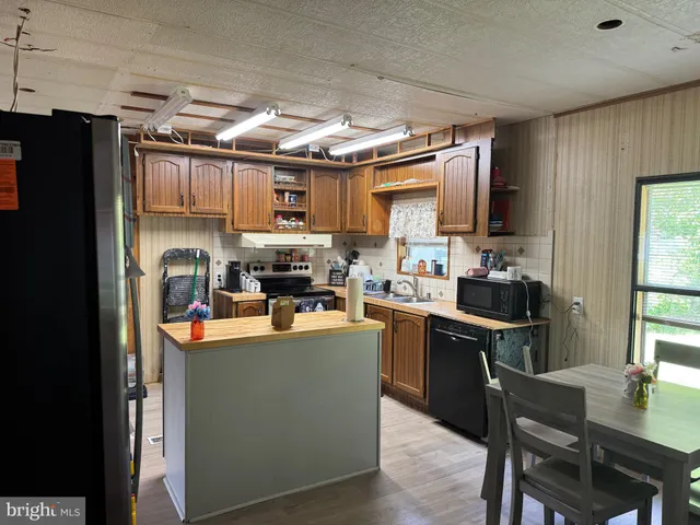 a kitchen with kitchen island a refrigerator a stove a sink dishwasher and wooden cabinets