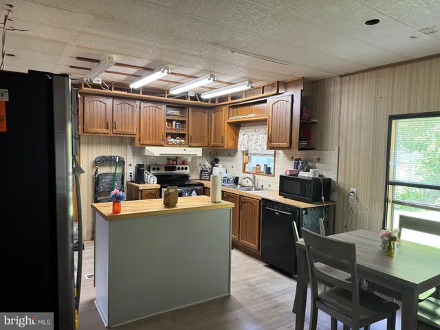 a kitchen with stainless steel appliances granite countertop a table chairs refrigerator and microwave