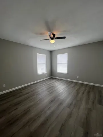 a view of an empty room with a ceiling fan and wooden floor