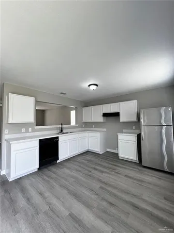 a large kitchen with stainless steel appliances granite countertop a stove a sink dishwasher and a refrigerator with wooden floor