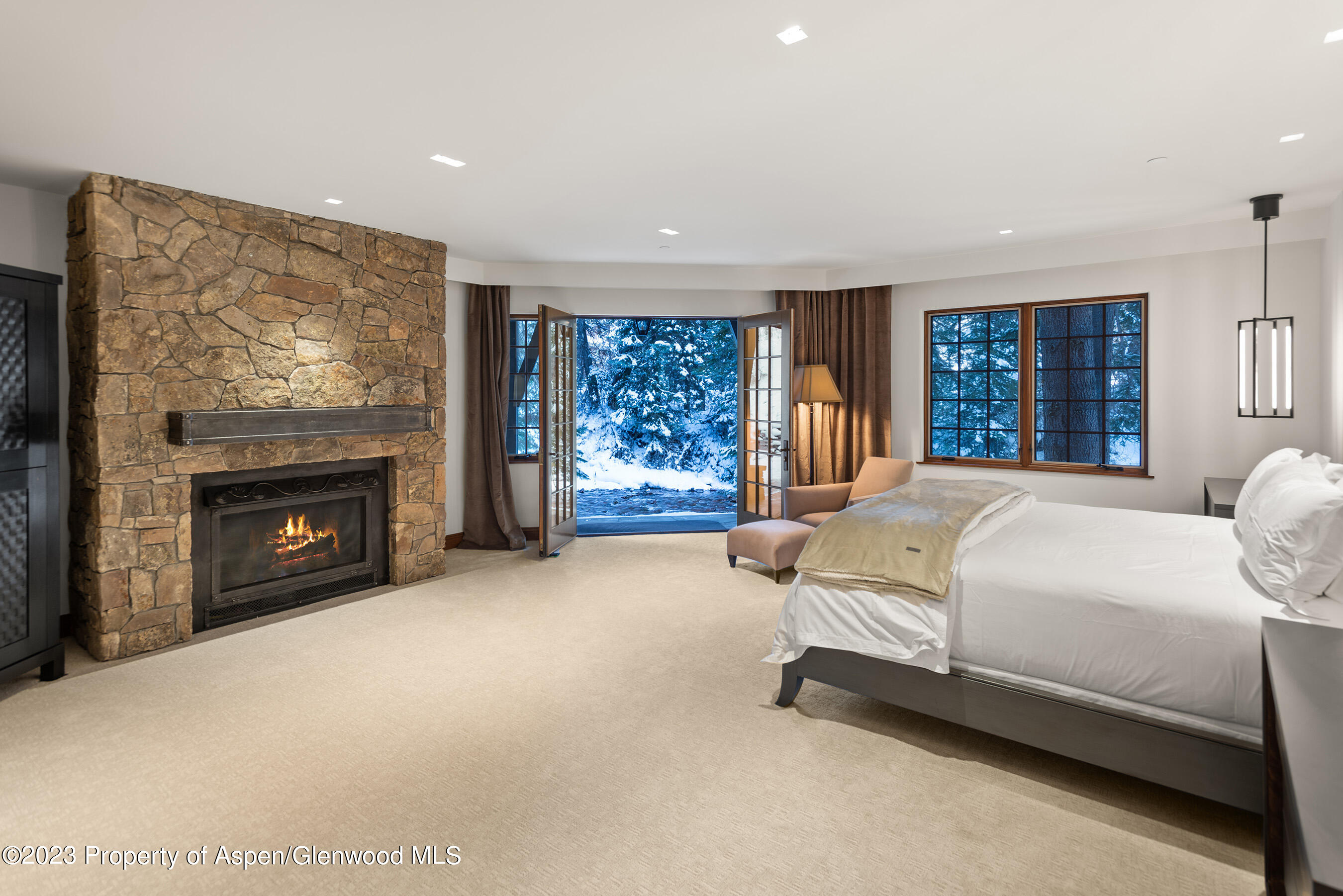 1819 Maroon Creek Road Aspen, CO 81611 - Photo 25 of 43 a spacious bedroom with a large bed and a fireplace