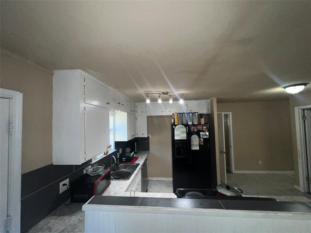 9104 Farmers Road White Settlement, TX 76108 - Photo 12 of 40 Kitchen featuring white cabinetry, black fridge with ice dispenser, track lighting, and dishwasher
