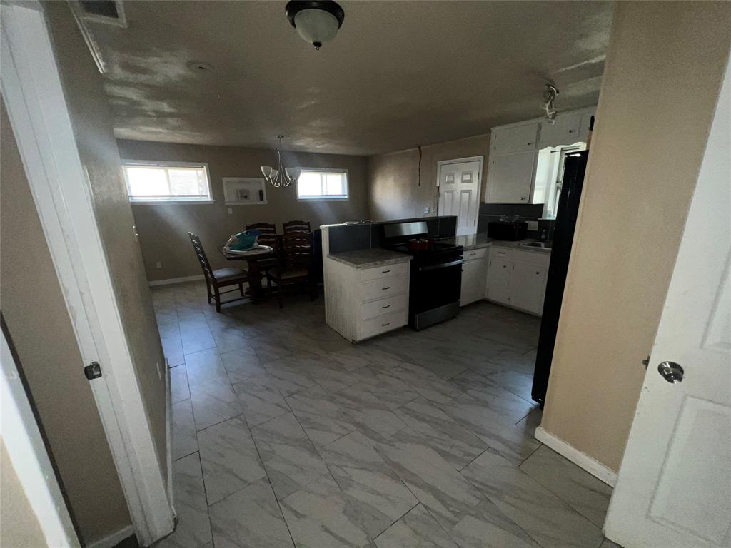9104 Farmers Road White Settlement, TX 76108 - Photo 20 of 40 Kitchen featuring white cabinetry, electric stove, a peninsula, light marble finish floors, and freestanding refrigerator