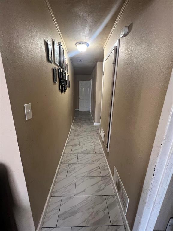 9104 Farmers Road White Settlement, TX 76108 - Photo 26 of 40 Hallway featuring light marble finish flooring, a textured ceiling, and a textured wall