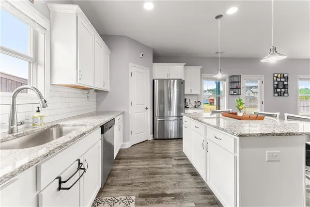 a kitchen with granite countertop kitchen island a sink stainless steel appliances and white cabinets