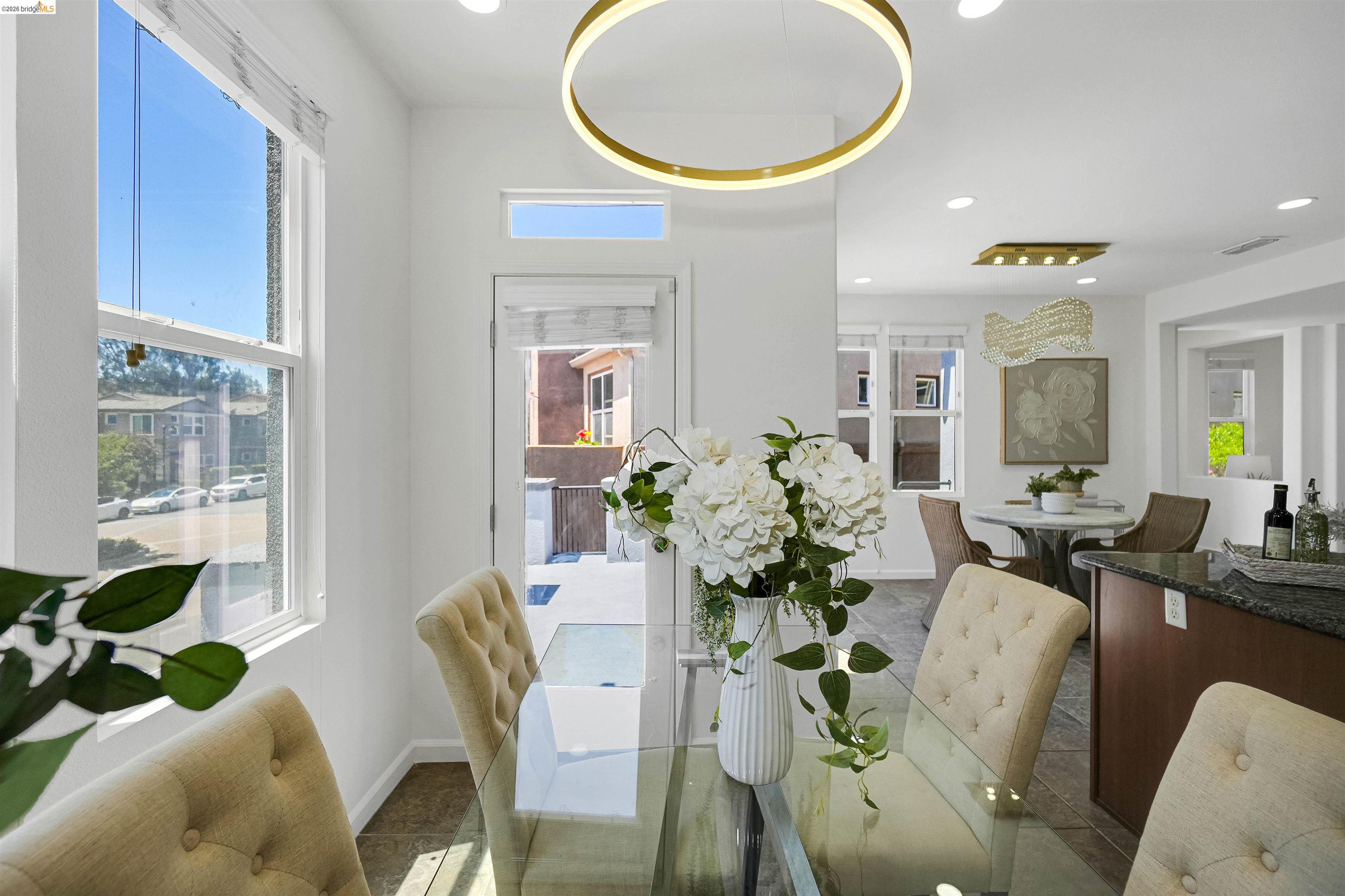 449 Constantine Court San Ramon, CA 94583 - Photo 25 of 63 Bright dining area featuring a modern circular chandelier, transom window, and a glass-top dining table