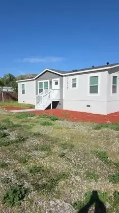 a front view of house with yard and trees in the background