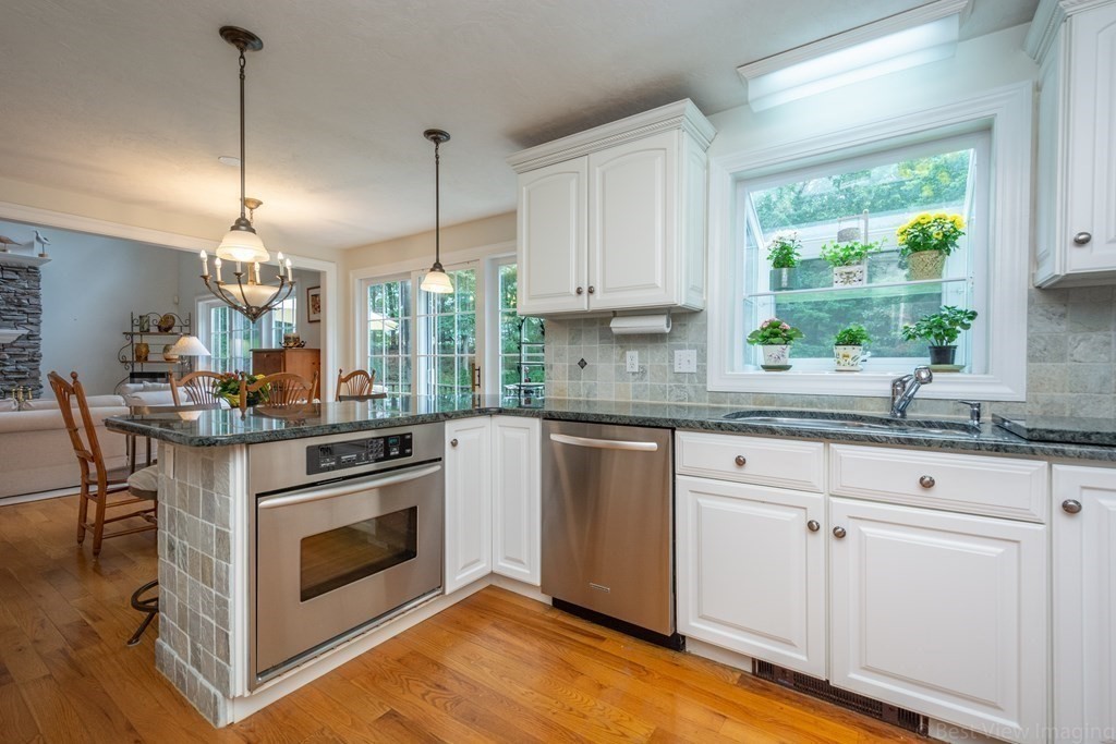 56 Powder Hill Road Bolton, MA 01740 - Photo 10 of 38 a kitchen with kitchen island a stove a sink and white cabinets with wooden floor