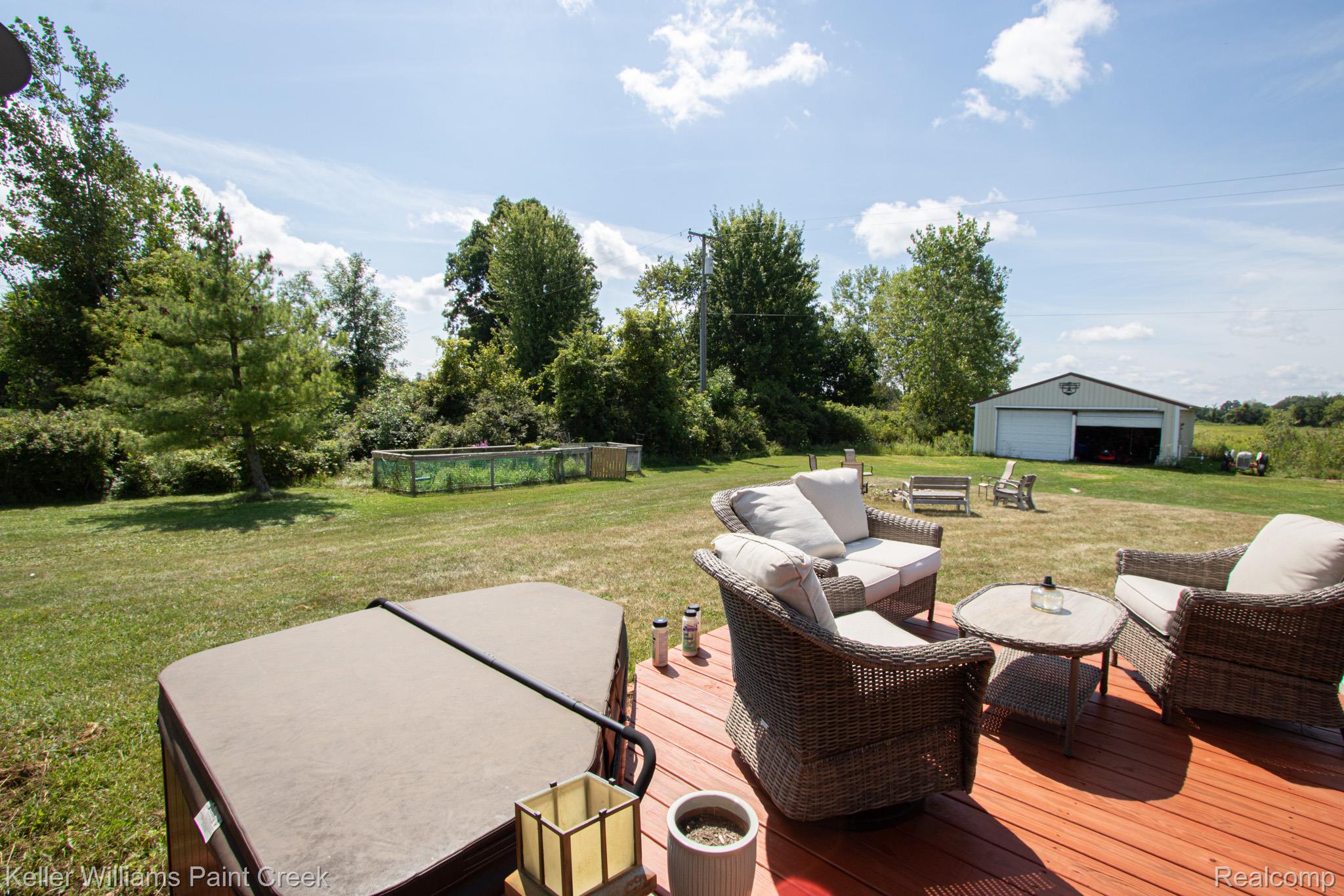 625 Howell Road Allenton, MI 48002 - Photo 36 of 46 Expansive backyard featuring a hot tub, a built-in deck, a large storage building, and an above-ground pool