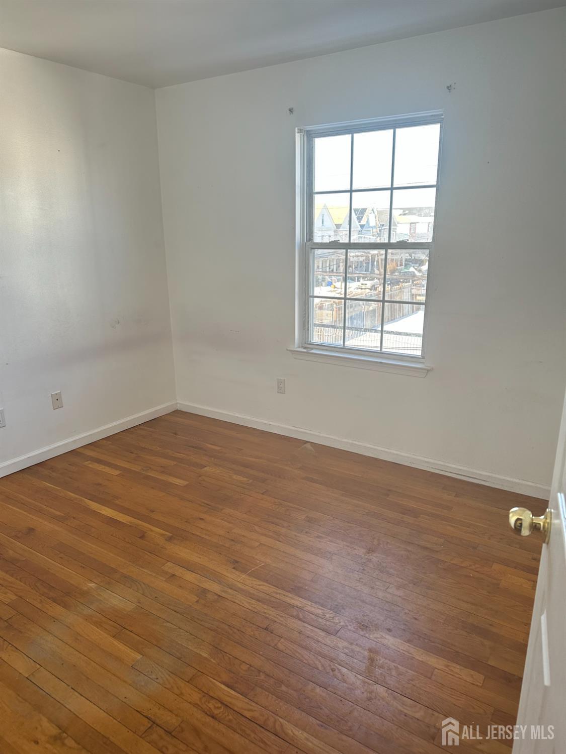 663 South Park Street Elizabeth, NJ 07206 - Photo 11 of 11 an empty room with wooden floor and windows