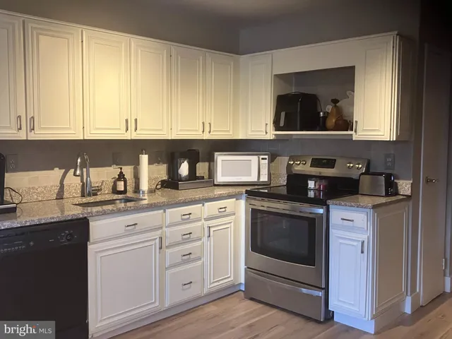 a kitchen with granite countertop white cabinets and white appliances