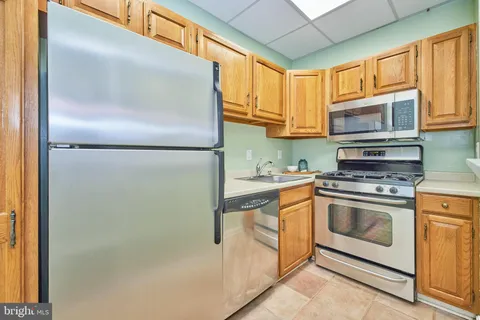 a kitchen with stainless steel appliances granite countertop a refrigerator a stove and a sink with large window