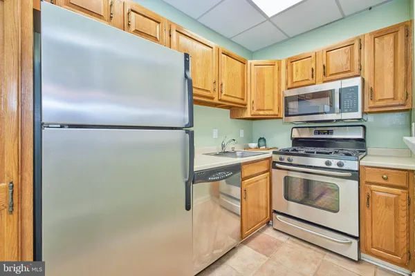 a kitchen with stainless steel appliances granite countertop a refrigerator a stove and a sink with large window